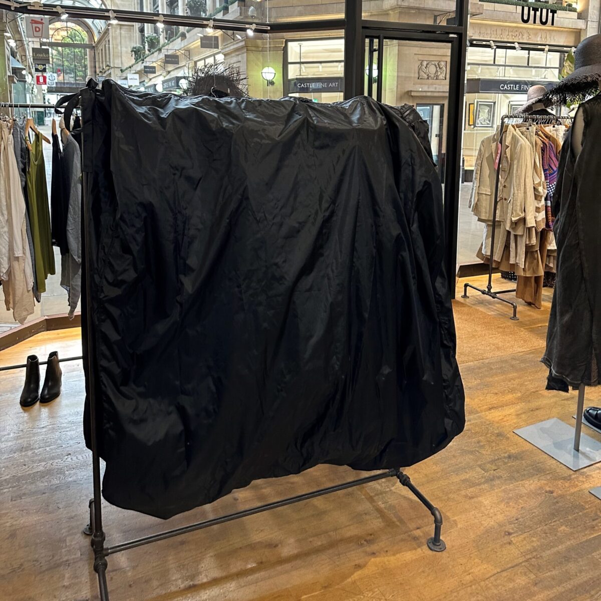 A 5ft black rail cover protecting garments at an exhibition.